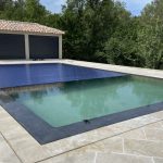Volet de piscine immergé se déployant dans le bassin en extérieur, en plein jour, à Montpellier.