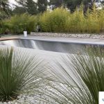 Volet immergé avec caillebotis en bois et lames en polycarbonate noir, en position fermée dans la piscine, photographié en plein jour en Occitanie.