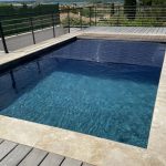 Volet immergé de piscine avec lames en polycarbonate noires, se déroulant dans la piscine, photographié en plein jour à Perpignan.