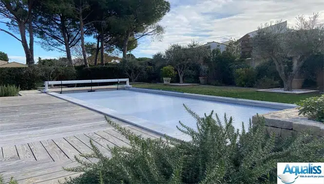 Volet de piscine mobile gris, en position fermée sur une piscine à Nîmes, photographié en journée.