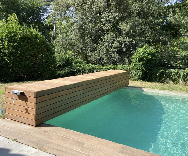 Volet de piscine hors sol avec coffre en bois, en position ouverte sur la piscine, photographié en pleine journée à Nîmes.