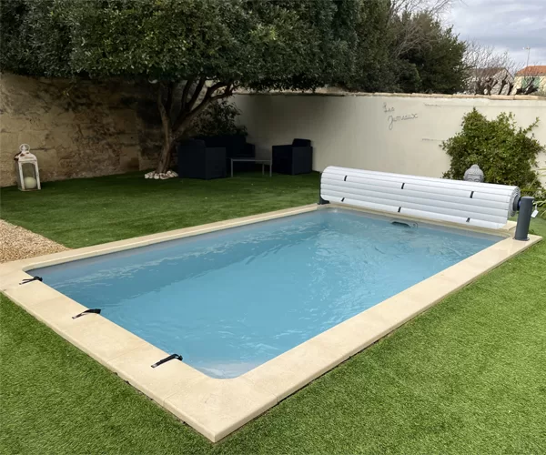 Volet de piscine hors sol de couleur gris anthracite, en position enroulée au-dessus d'une piscine 8x4 m à Marseille, photographié en journée.