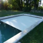 Volet de piscine immergé de couleur blanc, en train de se dérouler dans une piscine 8x4 m à Nîmes, photographié en journée.
