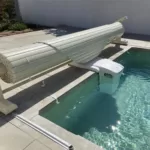 Volet de piscine sur rails, de couleur vanille, en position enroulée à Nîmes, photographié en journée.