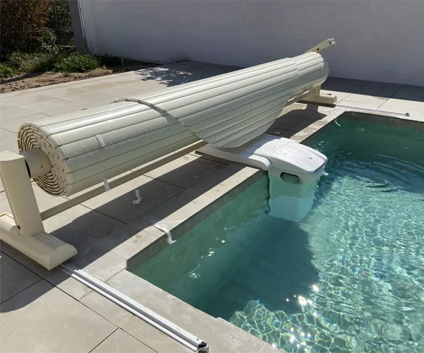 Volet de piscine sur rails, de couleur vanille, en position enroulée à Nîmes, photographié en journée.