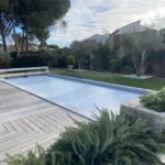 Volet de piscine mobile de couleur gris, en position fermé sur une piscine 8x4 m à Montpellier, photographié en journée.