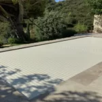 Volet de piscine immergé de couleur vanille, en position fermée sur une piscine à Montpellier, photographié en journée.