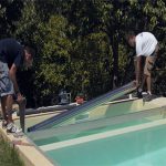 Mise en place de l'axe motorisé tubulaire dans la fosse technique de la piscine, fixé horizontalement juste au-dessus du fil d'eau.