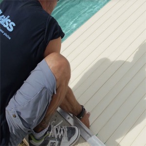 Raccordement des sangles du tablier à l'axe d'enroulement et installation des attaches de sécurité sur les margelles pour le verrouillage du volet.