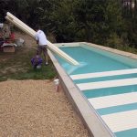 Assemblage manuel des lames du tablier de volet immergé flottant directement sur l'eau de la piscine durant l'installation.