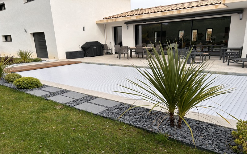 Volet de piscine immergé sur mesure avec lames grises, en position fermée sur une piscine à Nîmes, photographié en journée.